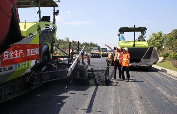 攤鋪機(jī)、壓路機(jī)等設(shè)備緊張有序運(yùn)行，高達(dá)170℃的瀝青混合料炙烤著公路人